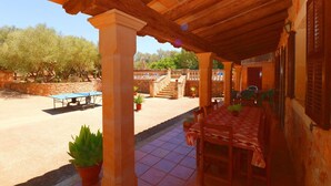 An outdoor patio with a table and chairs, a ping pong table, and potted plants. - Tranquil country house Can Guillem with pool, terrace, Wi-Fi and air conditioning (Campos)