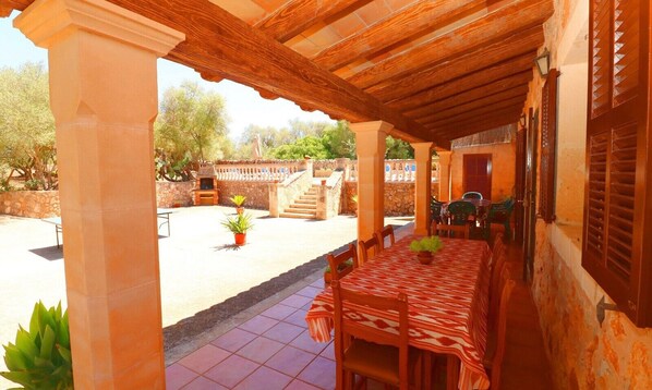 An outdoor patio with a covered dining area, stone walls, and potted plants. - Tranquil Country Home Can Guillem with Pool, Terrace, Wi-Fi & Air Conditioning (Campos)