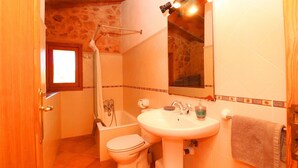 A bathroom with a toilet, sink, shower, and a mirror. - Tranquil country house Can Guillem with pool, terrace, Wi-Fi and air conditioning (Campos)