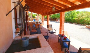 An outdoor patio with a covered seating area, a table with dishes, and a decorative metal gate.