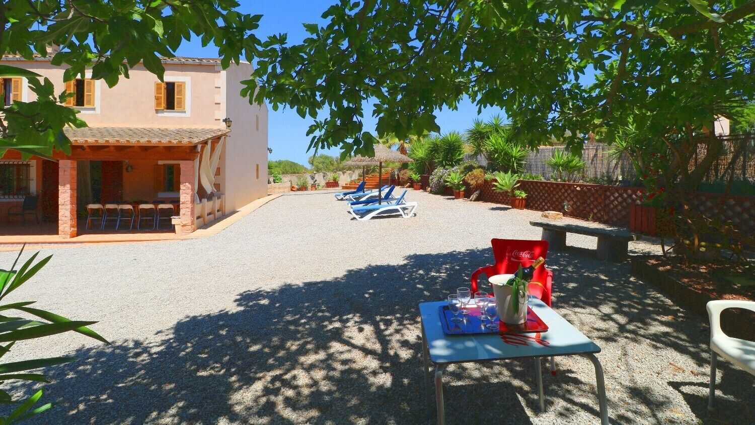 A courtyard with outdoor seating, a table with drinks, and a building with a tiled roof.