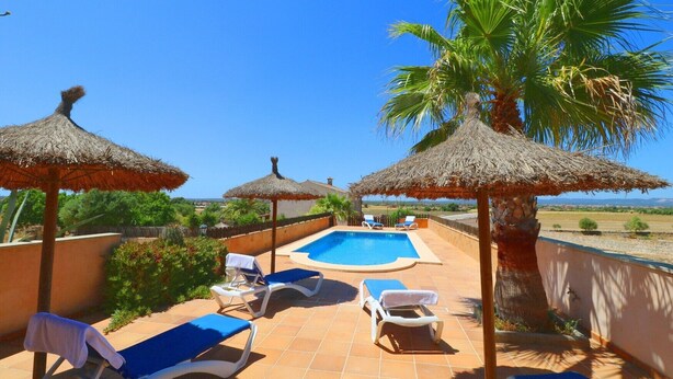 Une piscine sur le toit, avec des chaises longues et des parasols en chaume.
