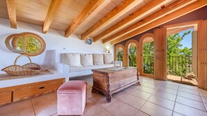 A spacious room with a wooden ceiling, a white sofa, a wooden chest, and a pink ottoman. - Finca "Son Antem" with private pool, garden, terrace, and Wi-Fi (Llucmajor)