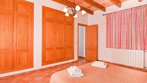 A bedroom with wooden wardrobes, a bed with a pink bedspread, and a radiator. - Can Mates Nou, private pool, free Wi-Fi (Campos)