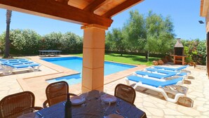 A poolside area with lounge chairs, a table set for dining, and a barbecue grill. - Can Mates Nou, private pool, free Wi-Fi (Campos)