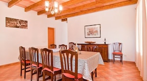 Une salle à manger avec un plafond en bois, un lustre, une table dressée pour six personnes et un buffet en bois sur lequel est posé un saladier.