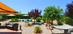 Un patio exterior con piscina, sillas de descanso y una hamaca.