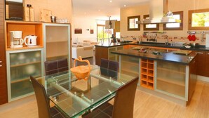 Una cocina moderna con una mesa de comedor de vidrio, armarios de madera y una isla integrada.