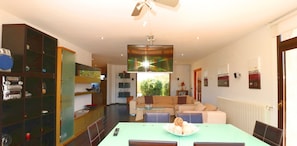 Una sala de estar moderna con sofá, mesa de comedor y televisor.