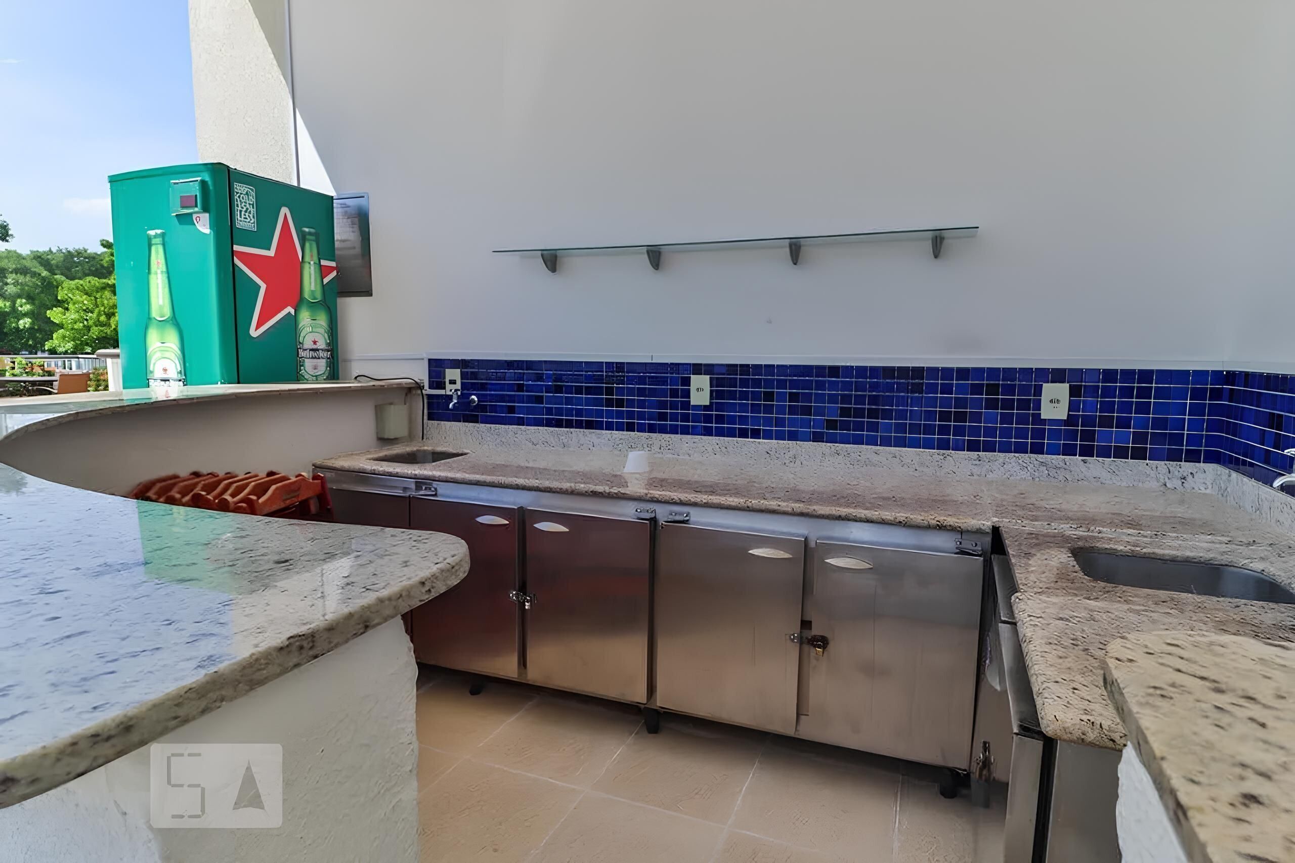 A kitchen with a blue-tiled backsplash, stainless steel cabinets, and a green refrigerator with a red star.