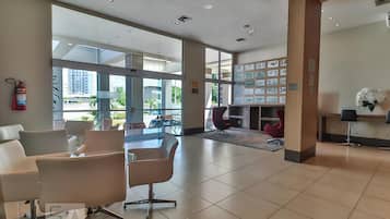 A spacious lobby with modern seating, a reception desk, and a wall displaying various informational posters.