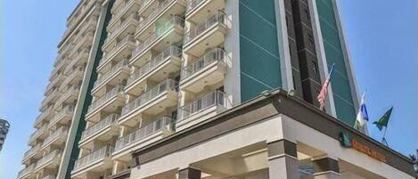 A tall, multi-story hotel with a prominent entrance and a flag on top.