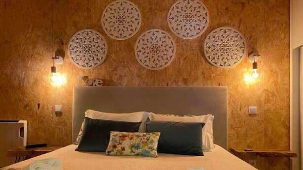 Ett hotellrum med en stor säng, flera kuddar, dekorativa väggpaneler och väggmonterade lampor.