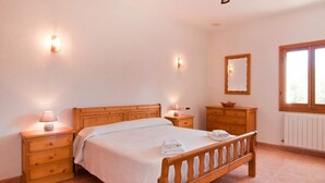 Un dormitorio con cama de madera, mesitas de noche, cómoda, espejo y ventana.