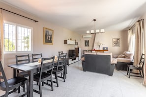 Una sala moderna con comedor, sofá, televisión y chimenea.