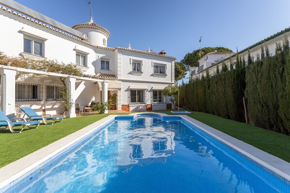 Una piscina con una casa blanca al fondo.