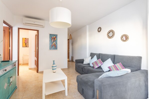 Una sala de estar con un sofá gris, una mesa blanca y un mueble azul turquesa.