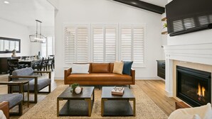 A modern living room with a brown leather sofa, two coffee tables, and a fireplace. - Arcadia 57 | Private Hot Tub * Resort Pool * Pinball * EV Charger (Santa Clara)
