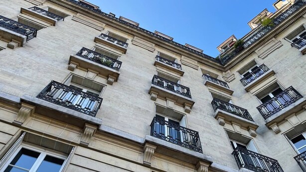 Un immeuble à plusieurs étages de style architectural classique, doté de balcons avec des garde-corps en fer forgé et de grandes fenêtres.