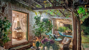 A cozy outdoor seating area with wicker furniture, a glass table, and a variety of plants.
