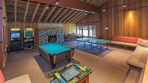 Una sala de recreación con mesa de billar, mesa de ping pong y juegos de arcade.