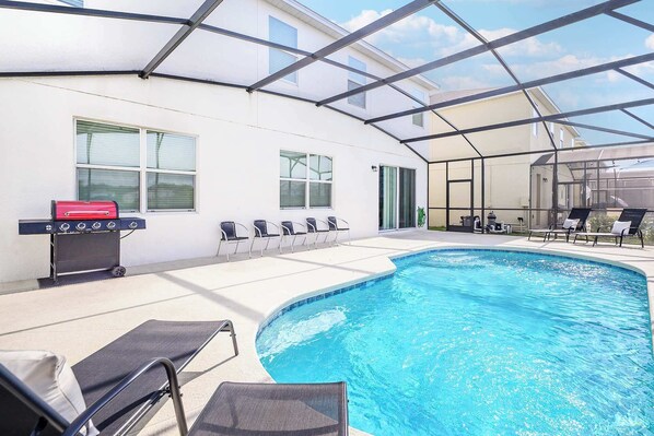 Una piscina interior con una parrilla y sillones de descanso.