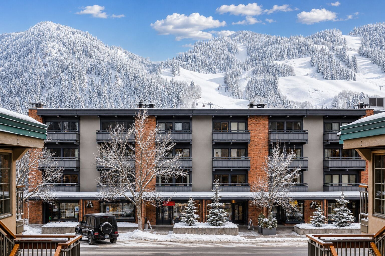 A multi-story hotel with a central courtyard, surrounded by snow-covered trees and mountains.