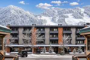 A multi-story hotel with a central courtyard, surrounded by snow-covered trees and mountains. - Walk to ski & Ajax Views (Aspen)