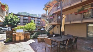 A patio with a grill, outdoor seating, and a staircase leading to an upper level. - Walk to ski & Ajax Views (Aspen)