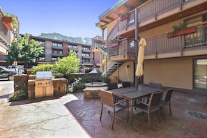 Une terrasse avec un barbecue, des sièges d’extérieur et un escalier menant à un niveau supérieur.