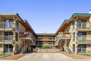 A multi-story hotel with a central courtyard, balconies with railings, and outdoor planters.