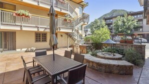 A patio with a table and chairs, a grill, and a stone fire pit. - Walk to ski & Ajax Views (Aspen)
