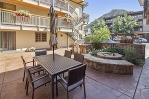A patio with a table and chairs, a grill, and a stone fire pit. - Walk to ski & Ajax Views (Aspen)
