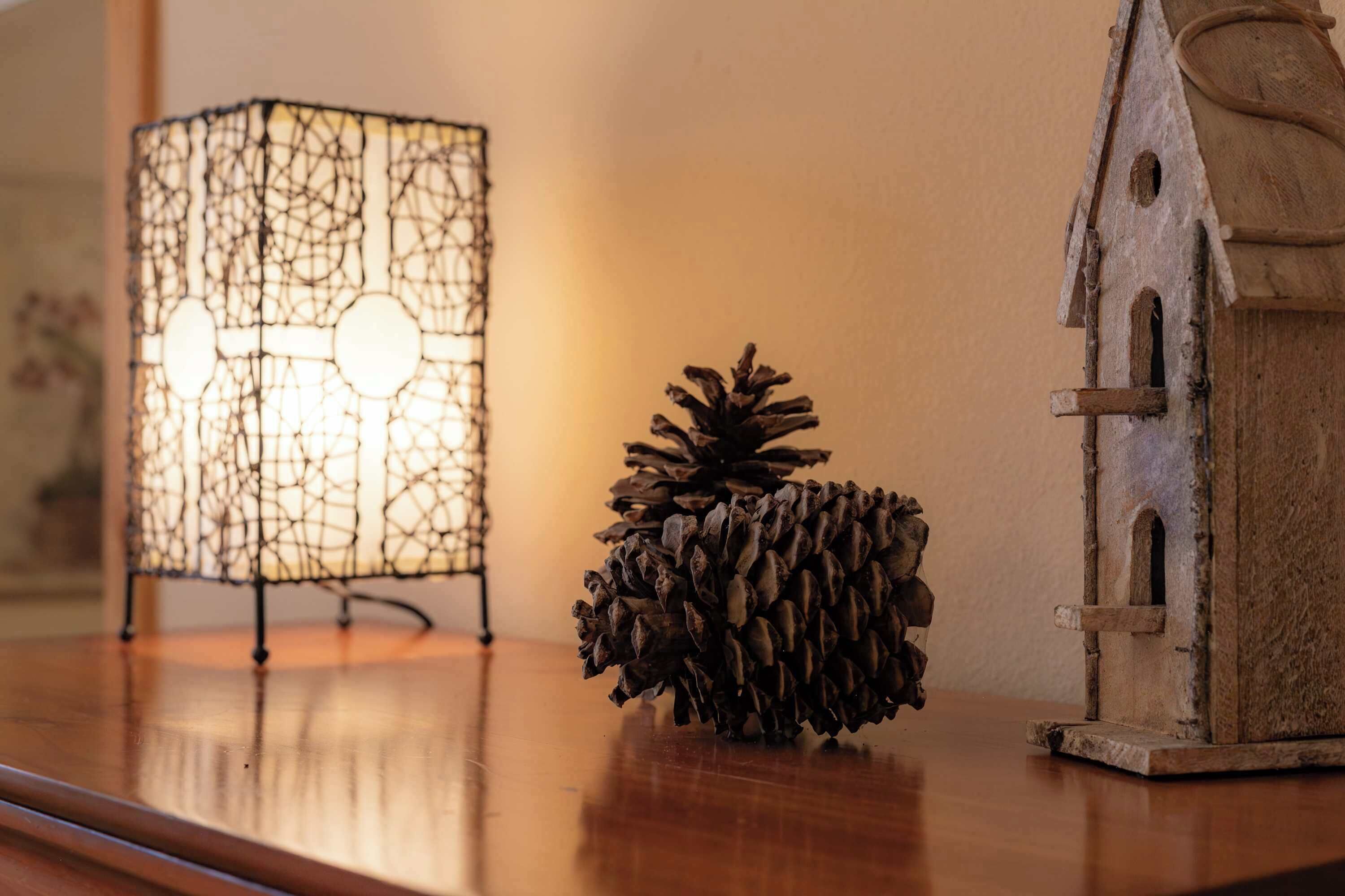 A wooden table with a pine cone and a small house model.