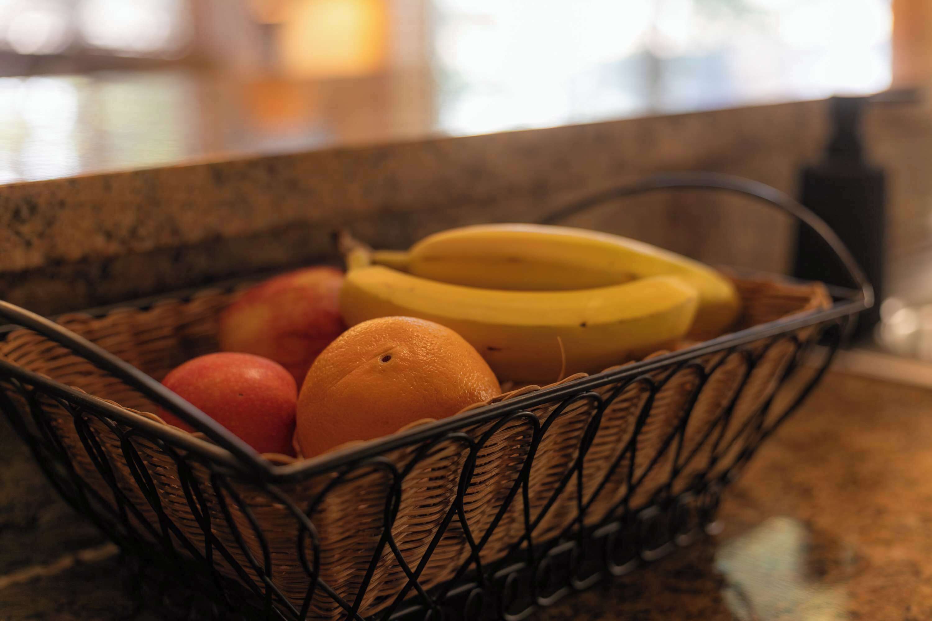 A basket containing fruits on a kitchen counter.