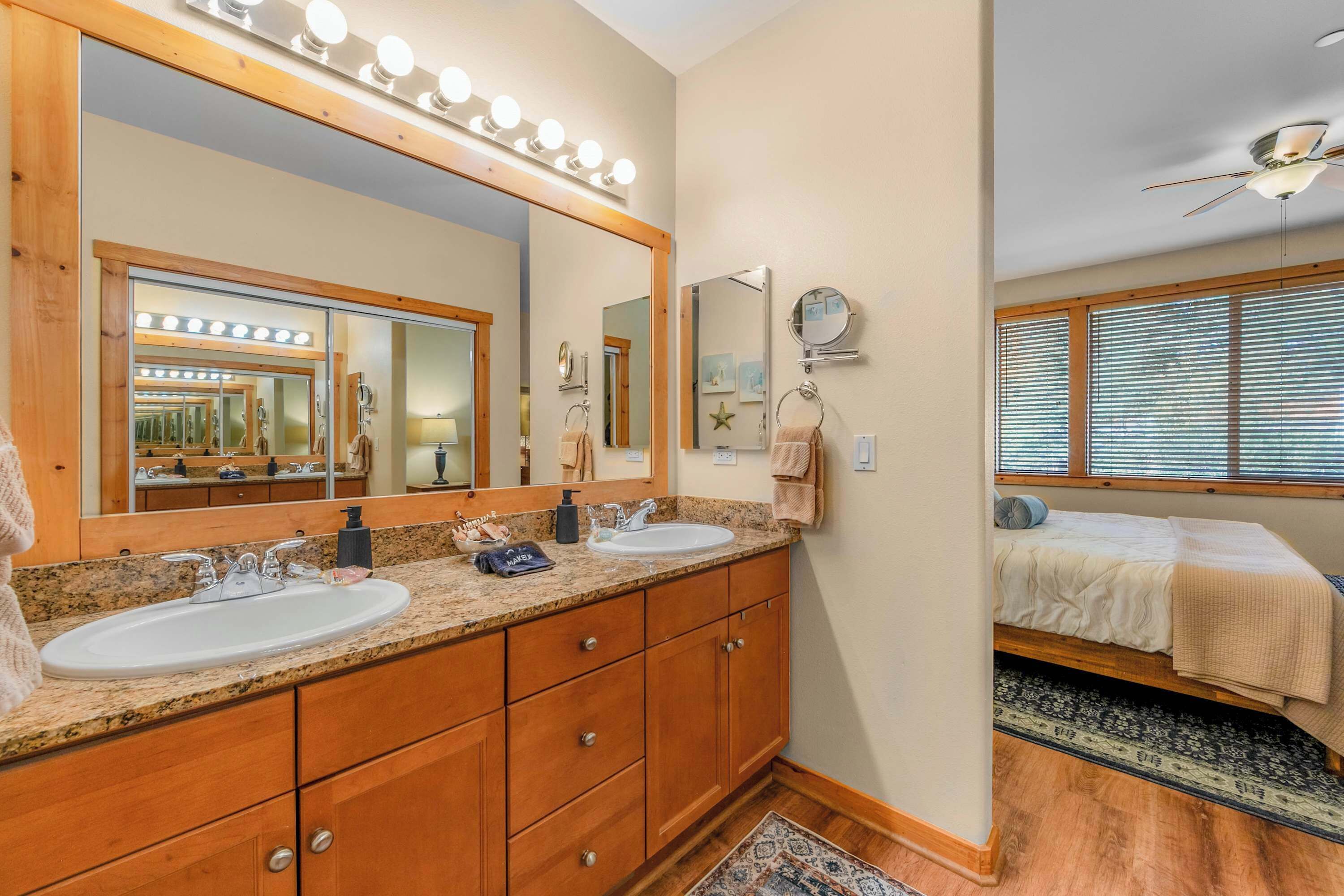 A bathroom with a vanity, double sink, large mirror, and vanity lights.
