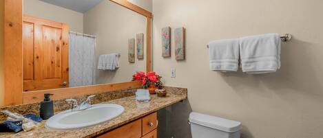 A bathroom with a sink, mirror, toilet, and towel rack.