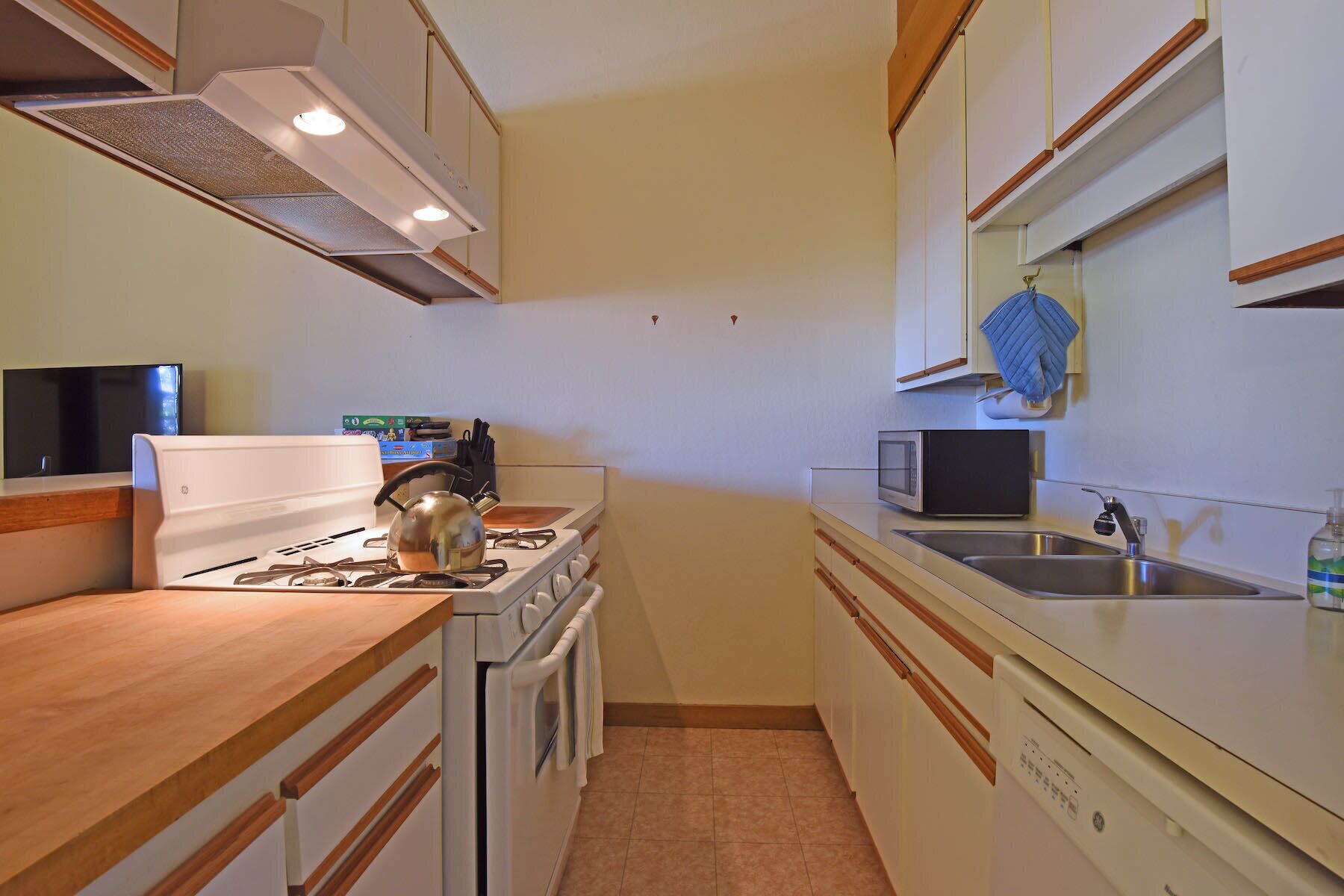 A compact kitchen with a stove, oven, microwave, and sink.