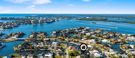 An aerial view of a coastal residential area with houses, boats, and a marina.