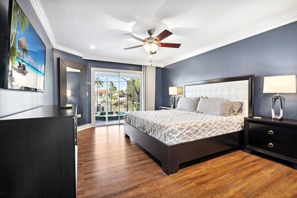 Un dormitorio moderno con una cama grande, un ventilador de techo y vistas a un balcón.