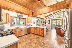A spacious kitchen with wooden cabinets, a large island, and a view of the outdoors.