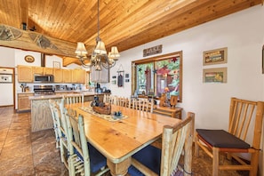 A wooden interior with a dining area, kitchen, and a view of the outdoors.