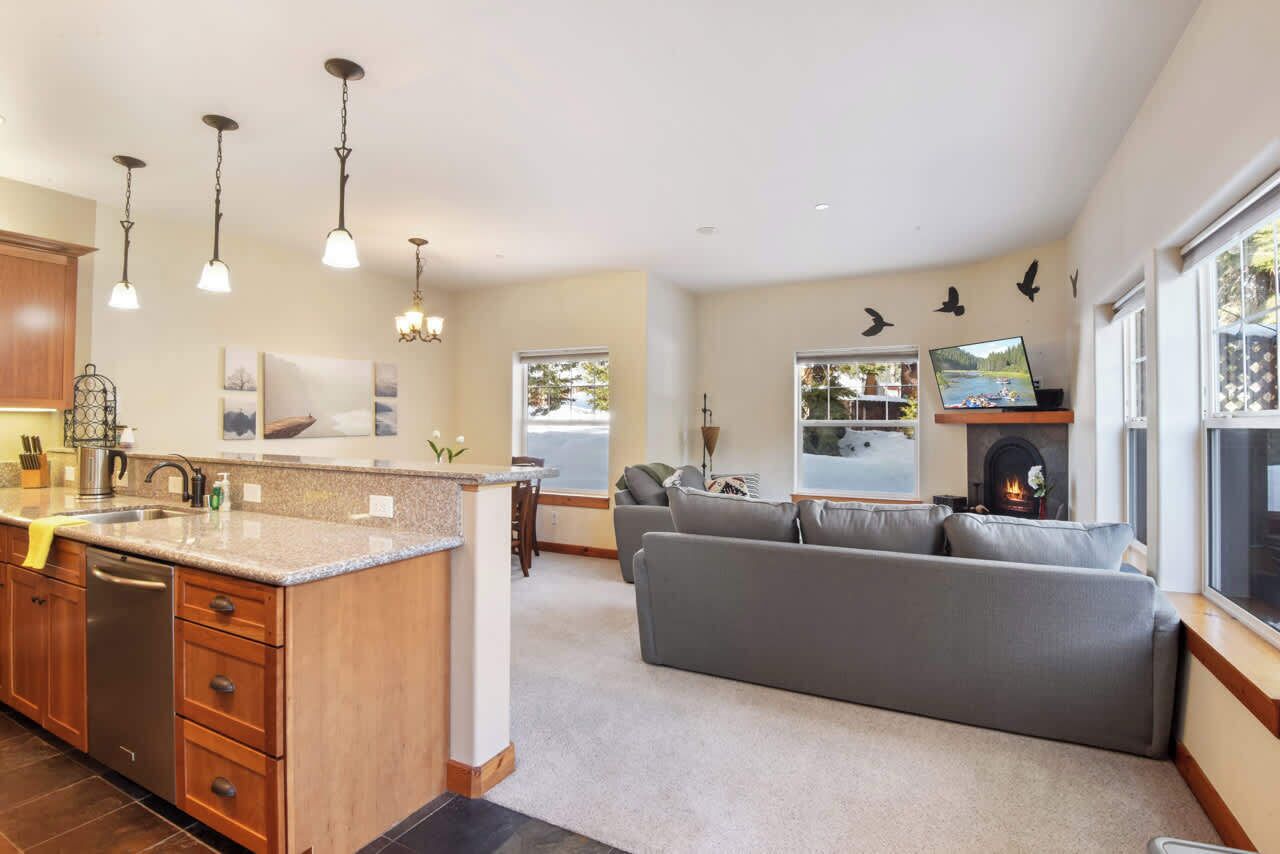 A modern kitchen with a central island, a grey sofa, and a fireplace.