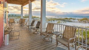 Eine Holzterrasse mit Sitzgelegenheiten und Blick auf den Strand.