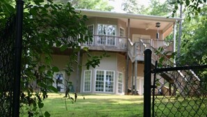A two-story house with a balcony, a front garage door, and a chain-link fence. - Blues Brothers Hideaway - Lakefront - Fenced yard - Pets Welcome - Clemson 20 mi (Fair Play)