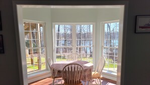A dining area with a table and chairs, large windows, and a view of the outdoors. - Blues Brothers Hideaway - Lakefront - Fenced yard - Pets Welcome - Clemson 20 mi (Fair Play)