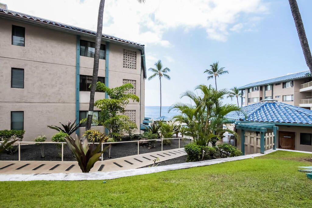 A hotel with a pool, palm trees, and a view of the ocean.