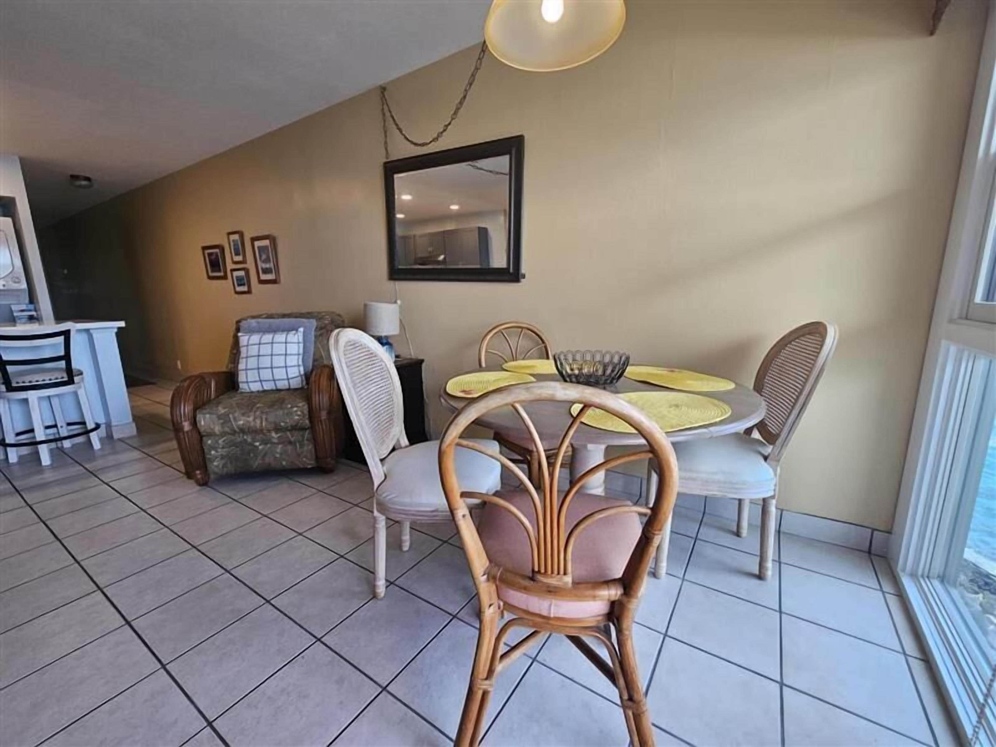 A dining area with wicker chairs and a round table, a sofa with a patterned cover, and a ceiling fan.