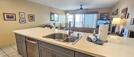 Una cocina moderna con una isla grande, pileta de acero inoxidable y muebles grises.