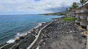 Un hôtel situé sur la côte, avec un rivage rocheux, une promenade dallée et une vue sur l’océan.